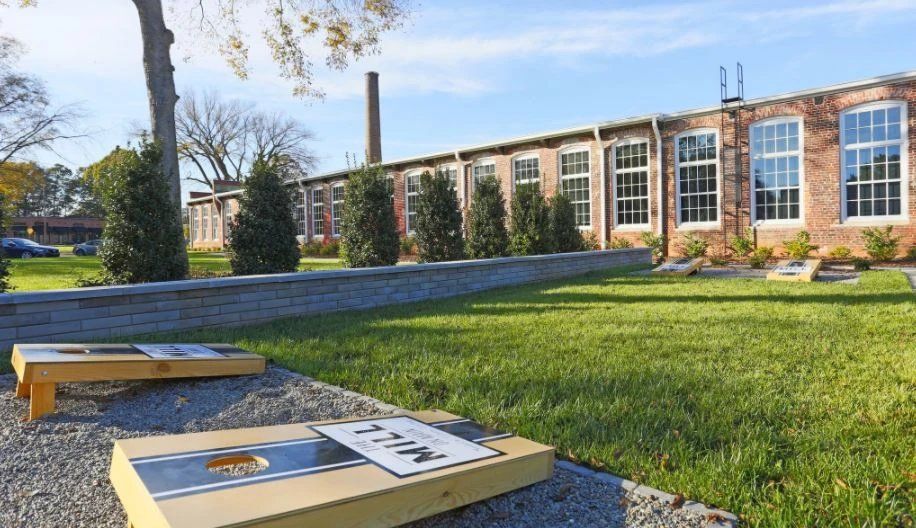 Exterior view of a property with a grassy area and cornhole games. At Waxhaw Mills, our apartments for rent in Waxhaw, NC offer the best in service and enviable amenities. Experience all our community has to offer. Contact us to set up a tour!