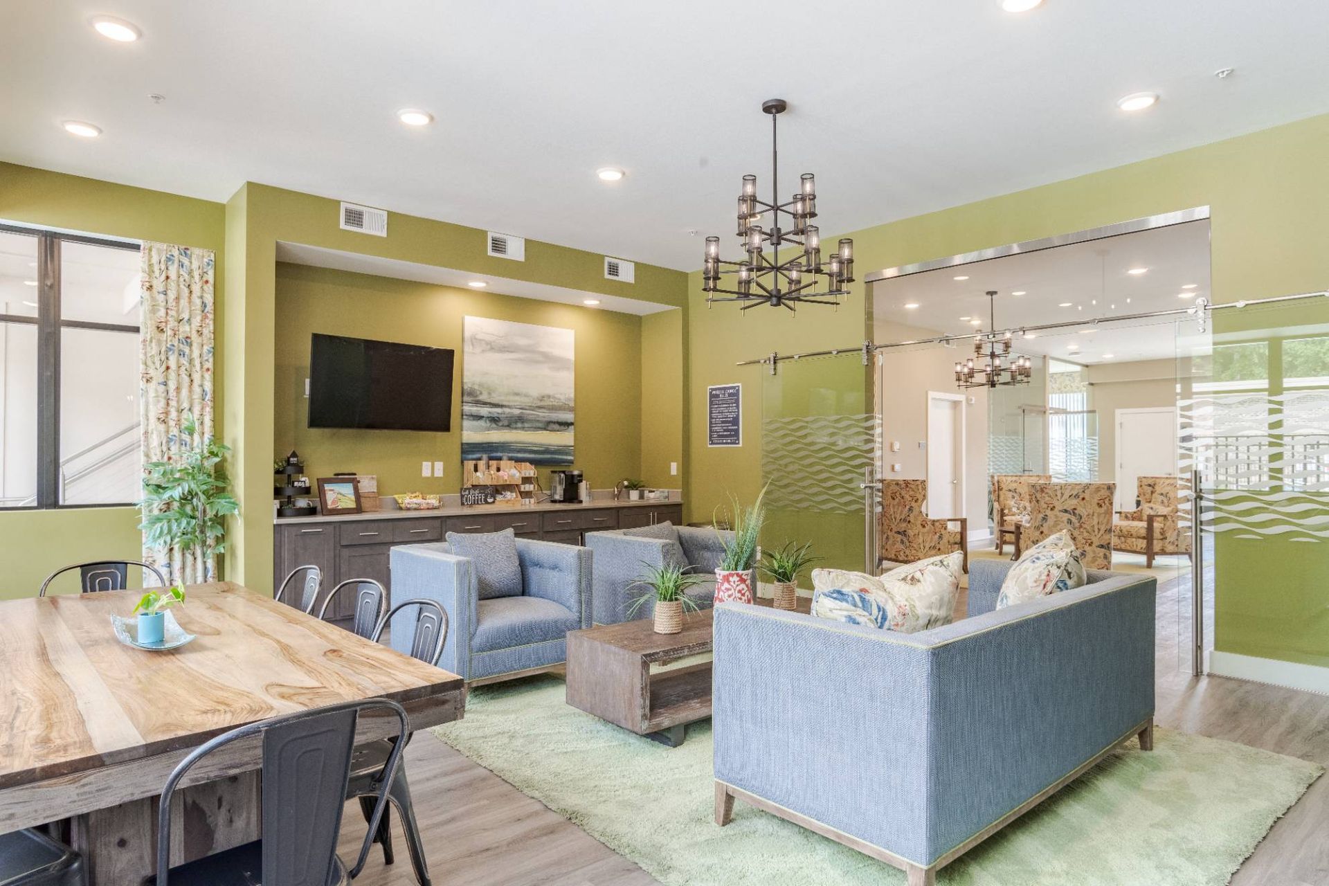 Interior of a modern community lounge with blue couches, a coffee bar, and a glass-walled area. At Waxhaw Mills, our apartments for rent in Waxhaw, NC offer the best in service and enviable amenities. Experience all our community has to offer. Contact us to set up a tour!