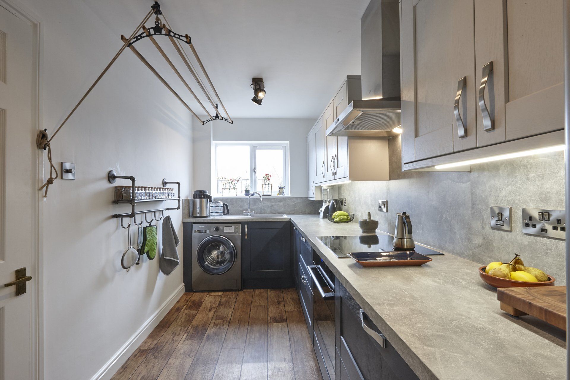 A kitchen with a washing machine , stove , sink , and cabinets.