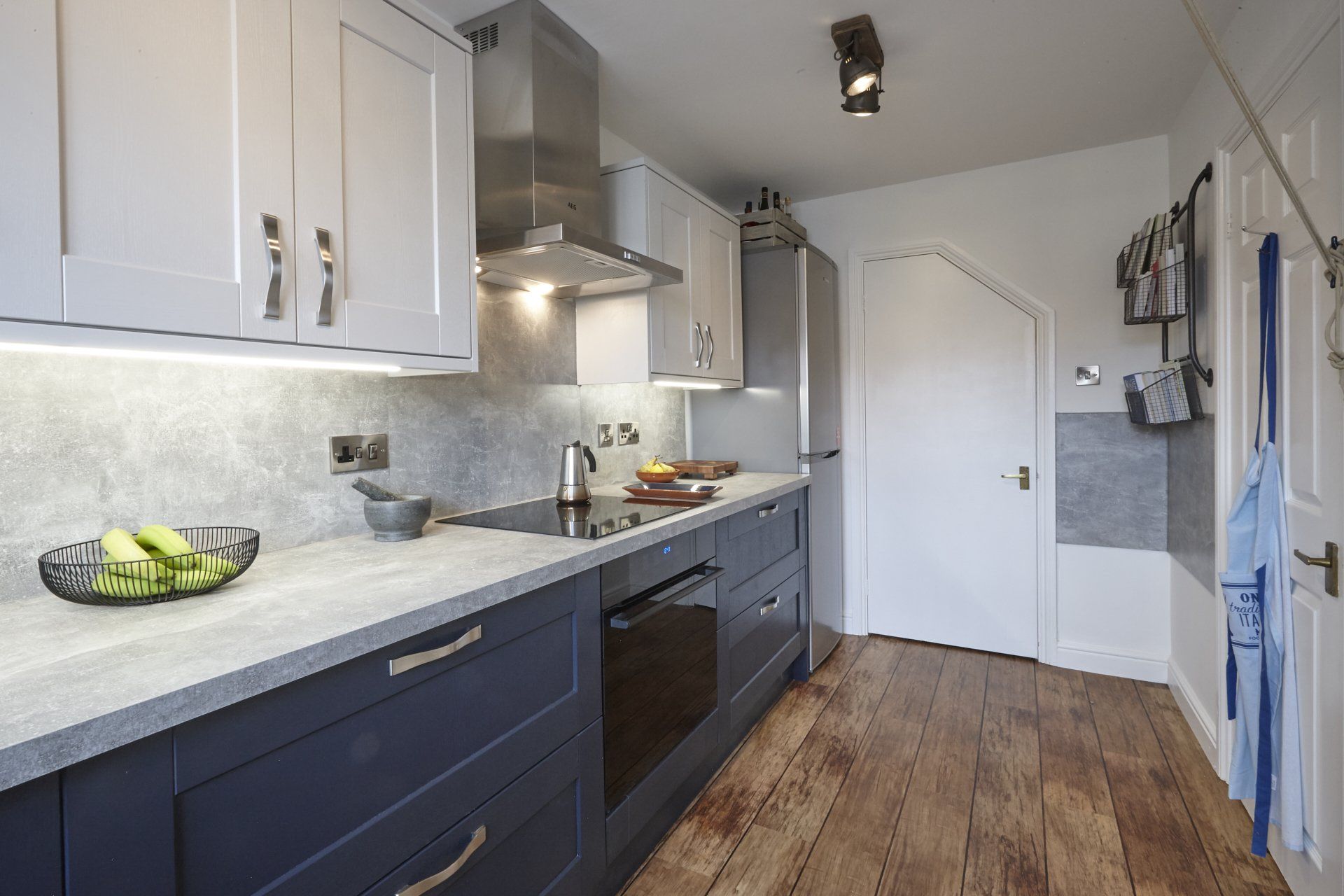 A kitchen with blue cabinets , white cabinets , stainless steel appliances and wooden floors.