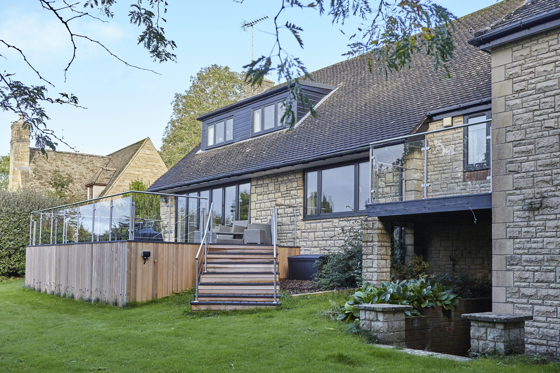 A large stone house with a large deck and stairs