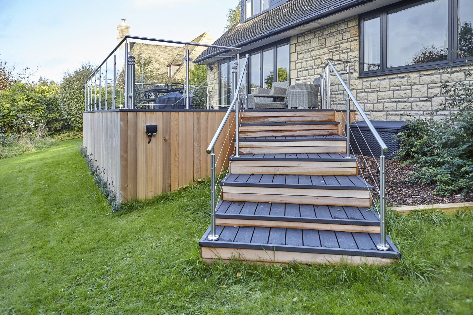 A wooden deck with stairs leading up to it in front of a house.