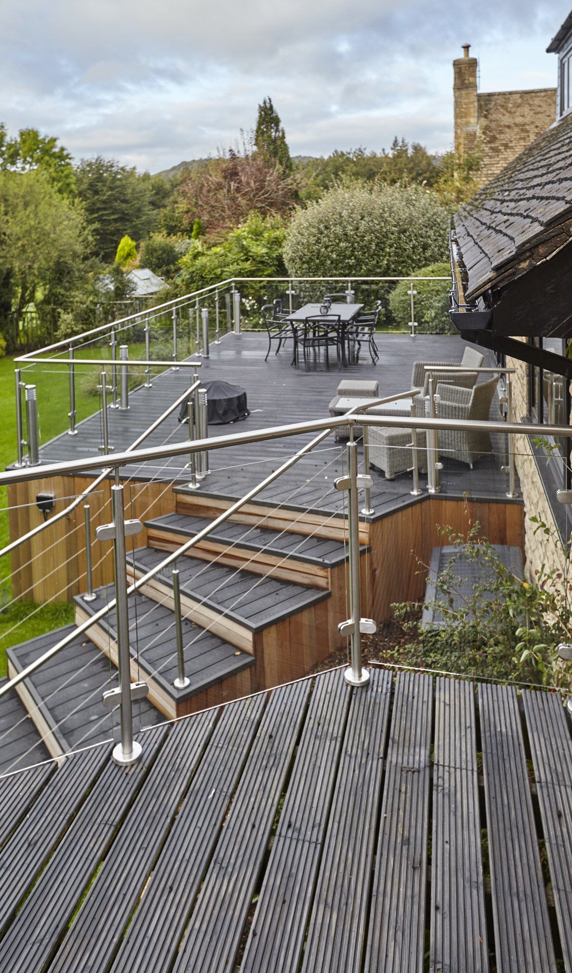A wooden deck with stairs and a stainless steel railing.