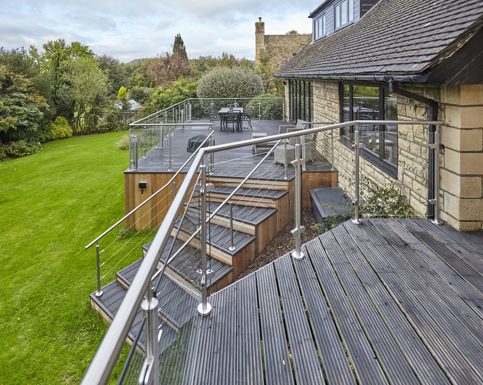 A wooden deck with stairs and a stainless steel railing.