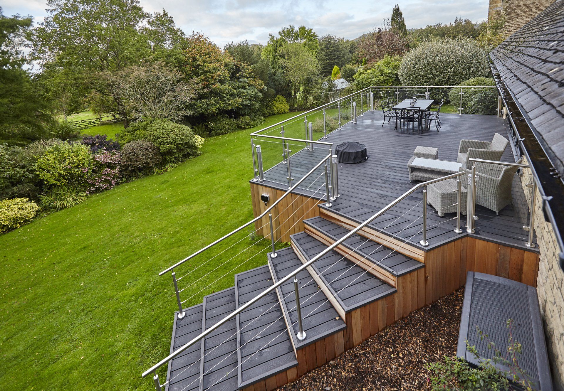 A wooden deck with stairs leading up to it and a table and chairs on it.