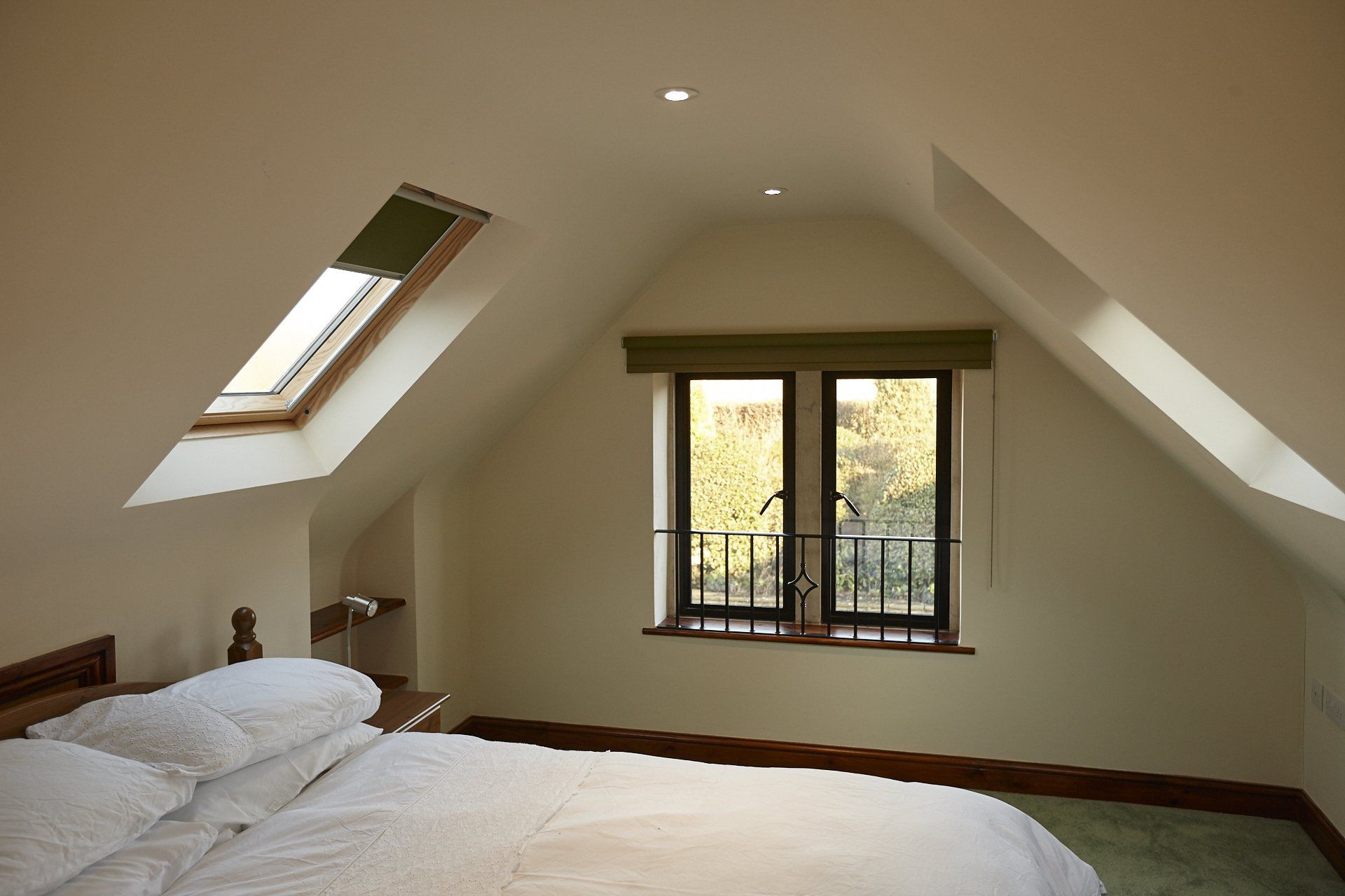 A bedroom with a bed and a window with a skylight