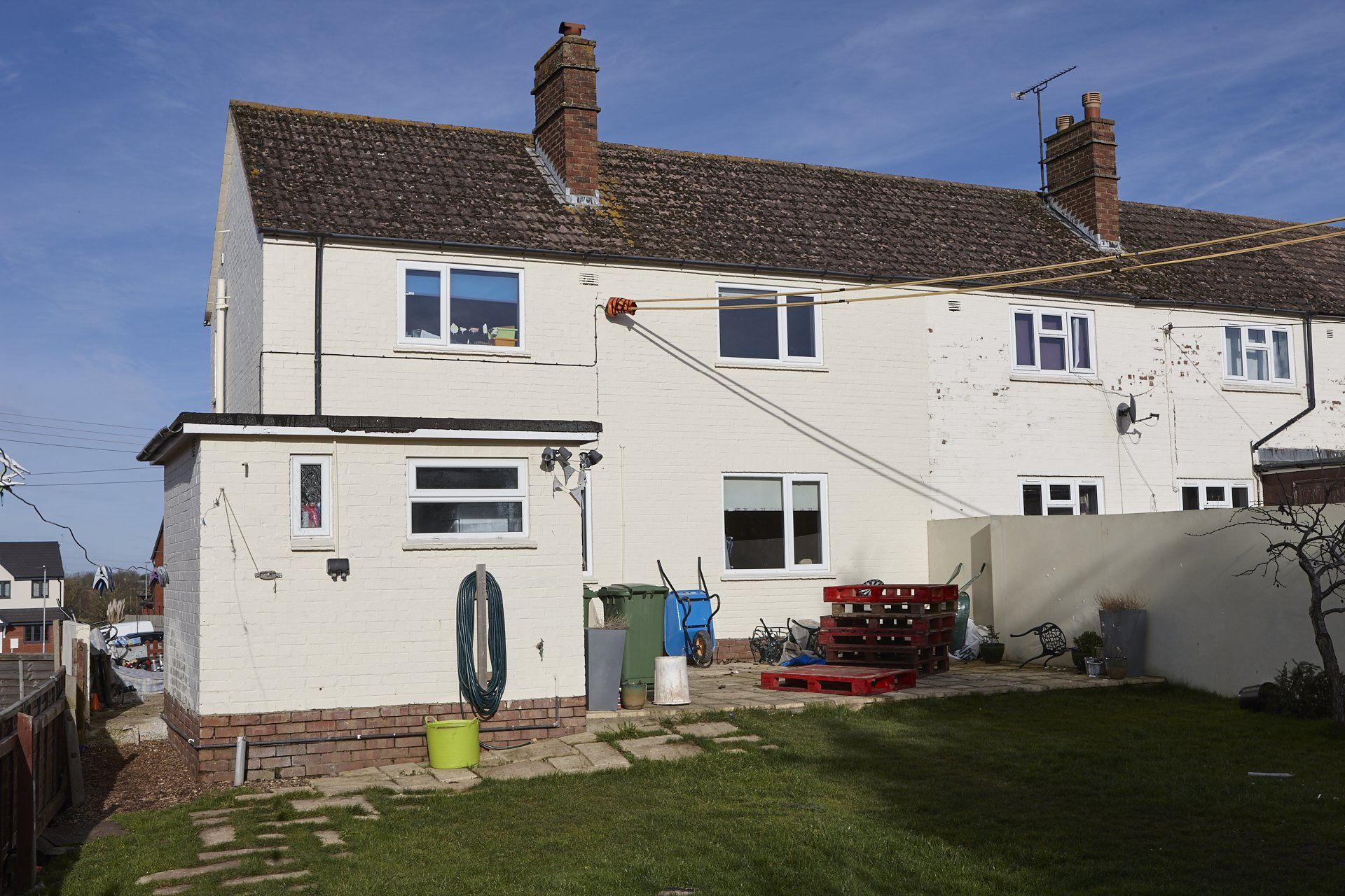 The back of a white house with a ladder in the backyard