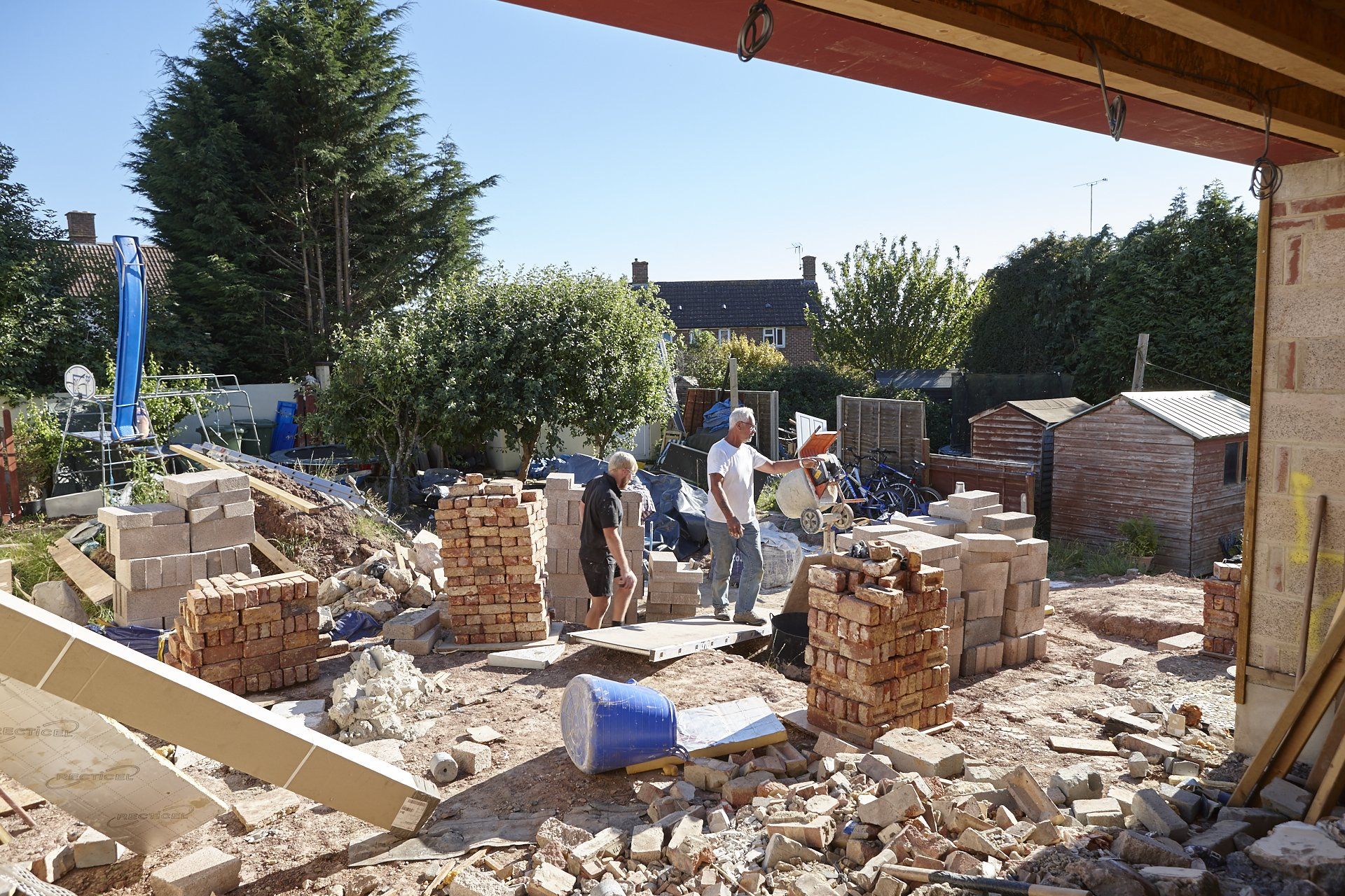 A group of people are standing in a pile of bricks on a construction site.