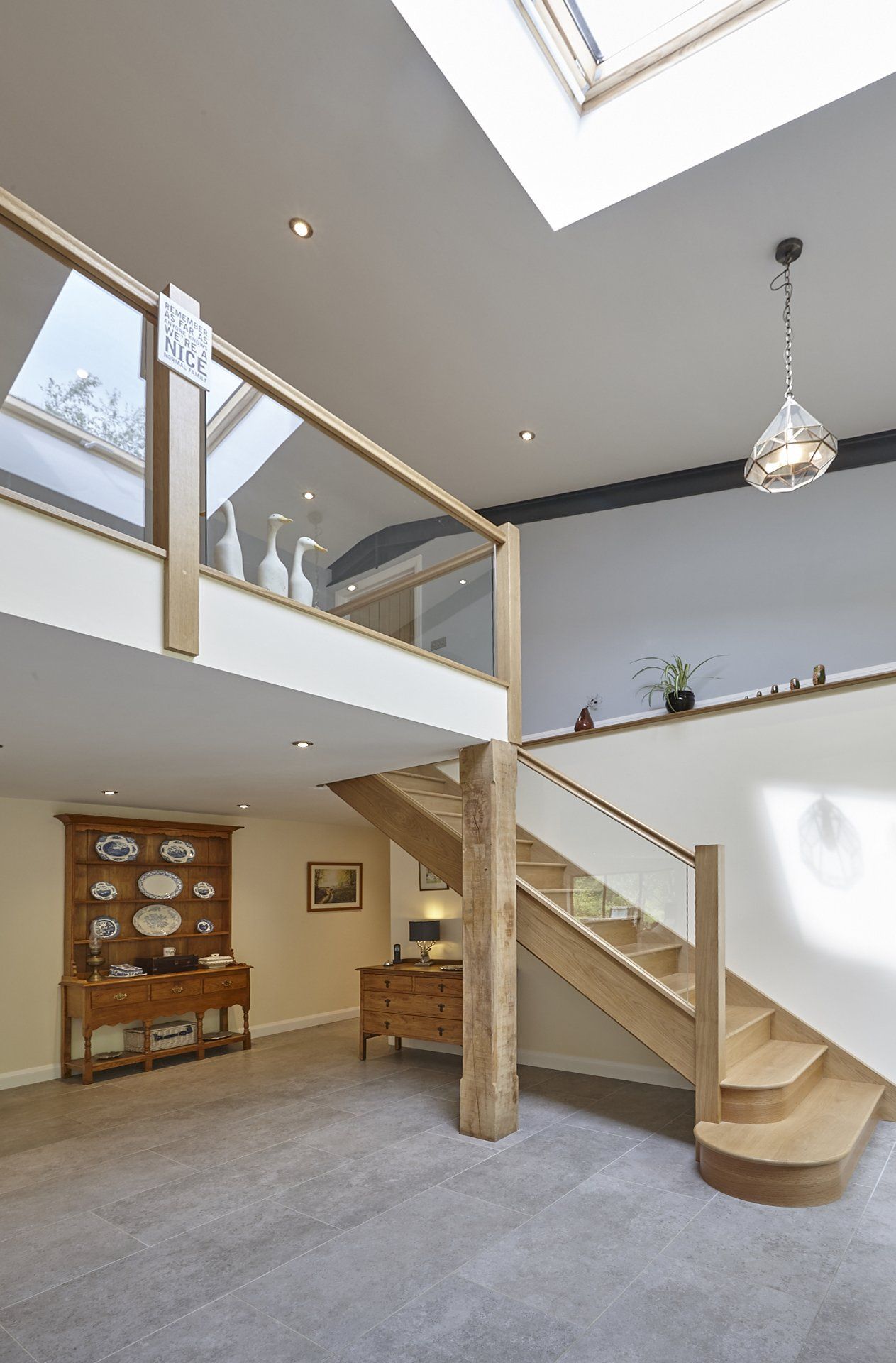 A wooden staircase with a glass railing in a room with a skylight.