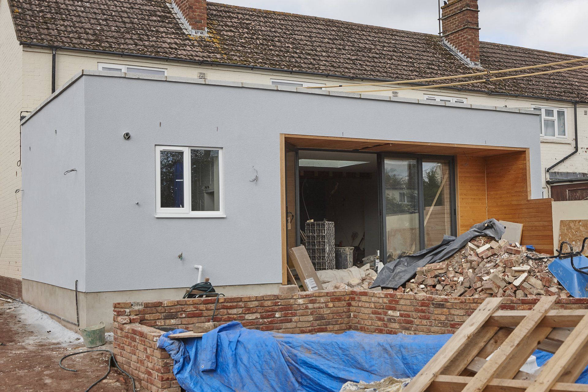 A house is being remodeled and a pile of bricks is in front of it.