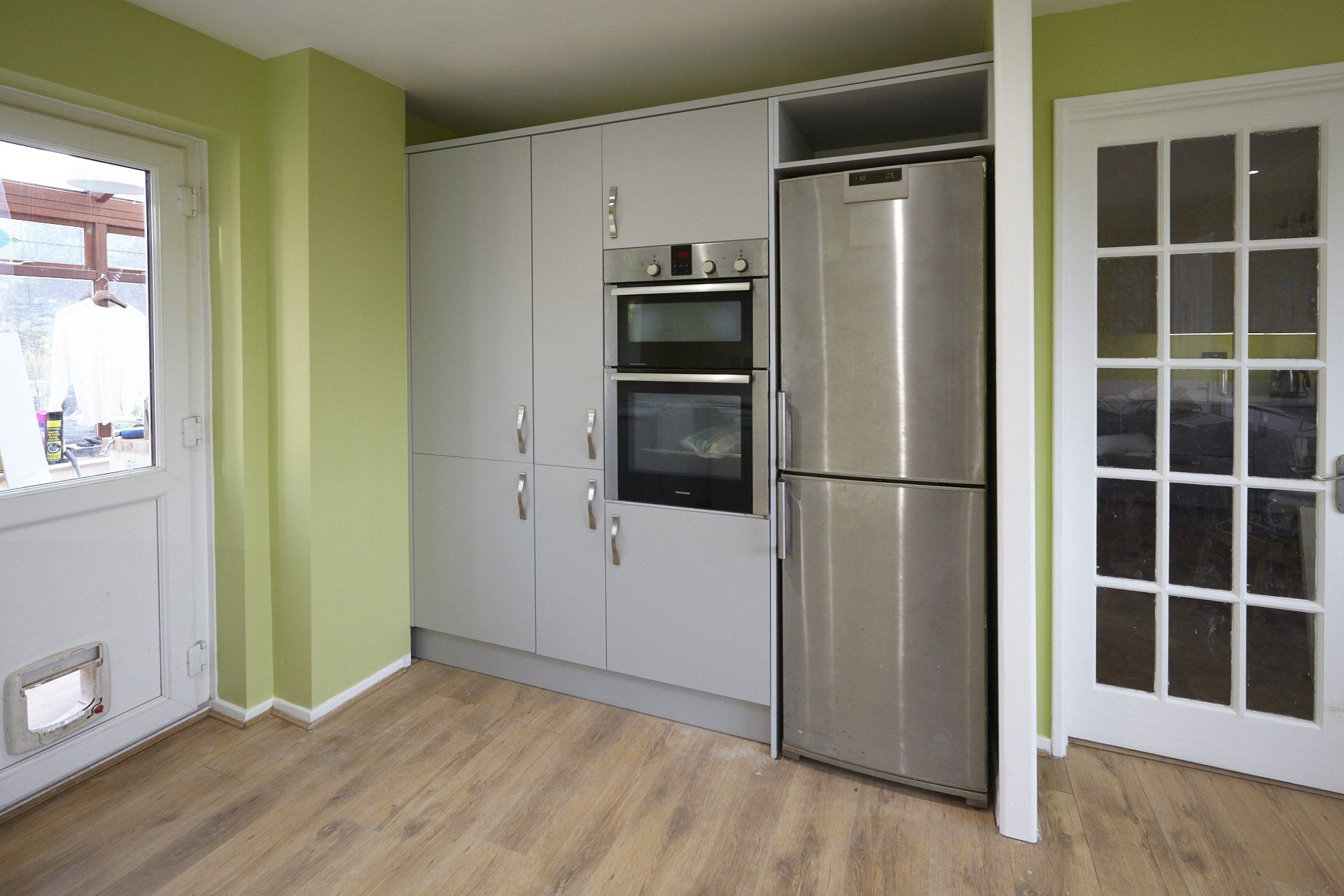 An empty kitchen with a stainless steel refrigerator and oven.
