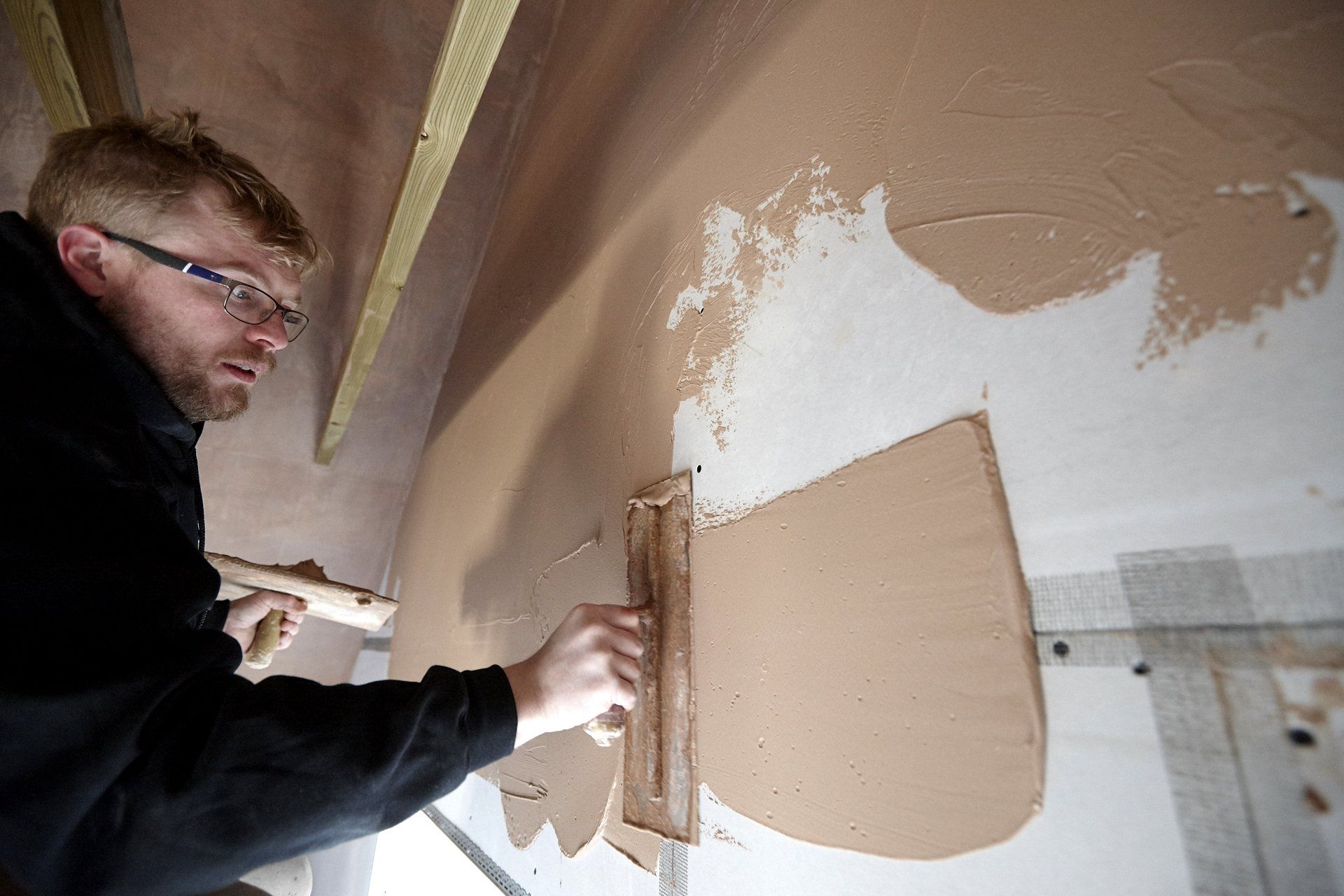 A man is plastering a wall with a trowel.