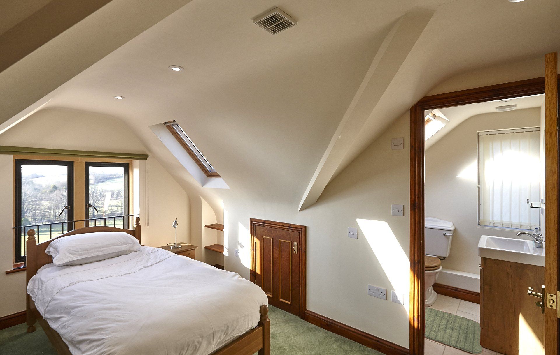 A bedroom with a bed and a bathroom in the background