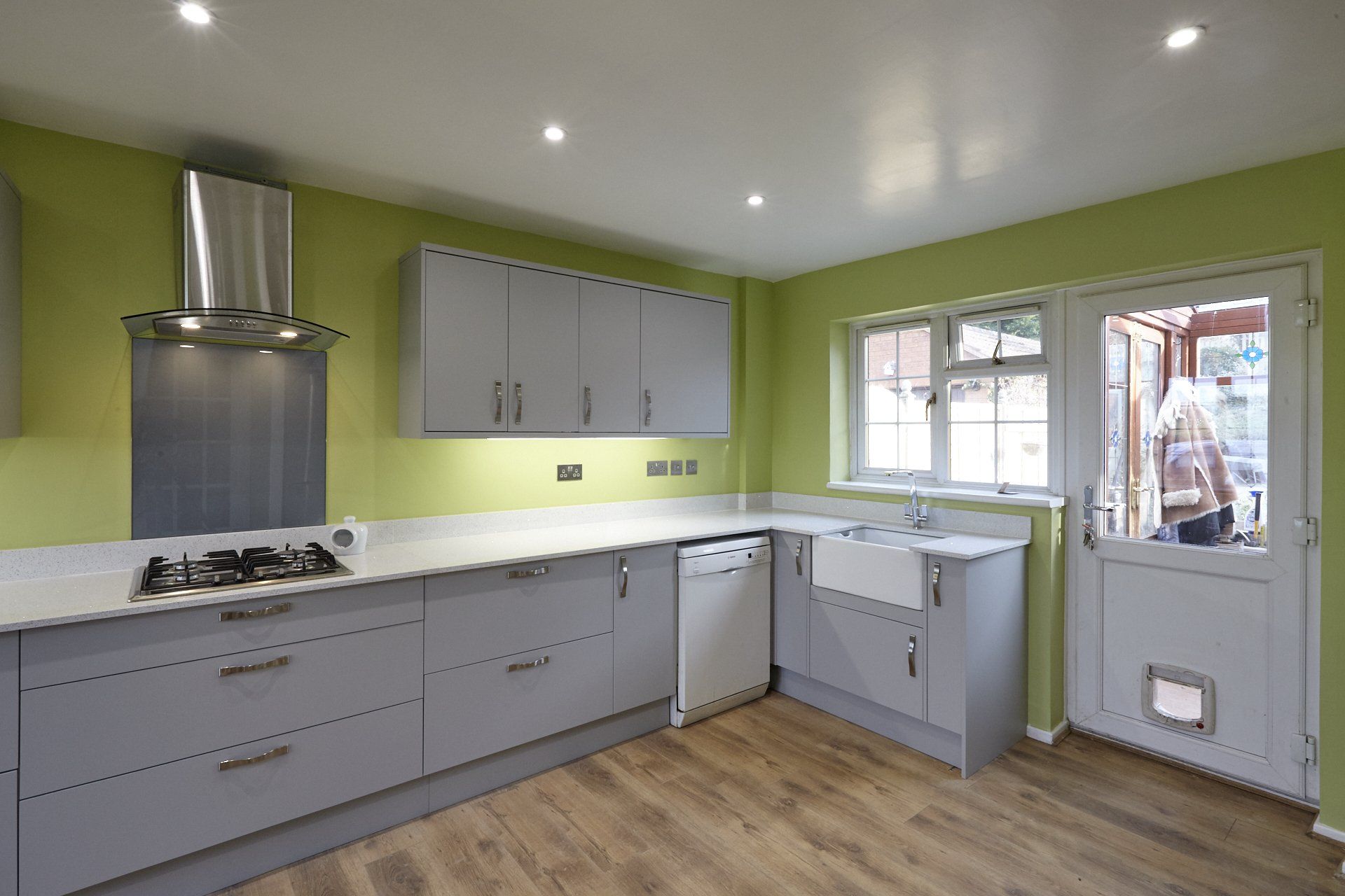 A kitchen with gray cabinets and green walls