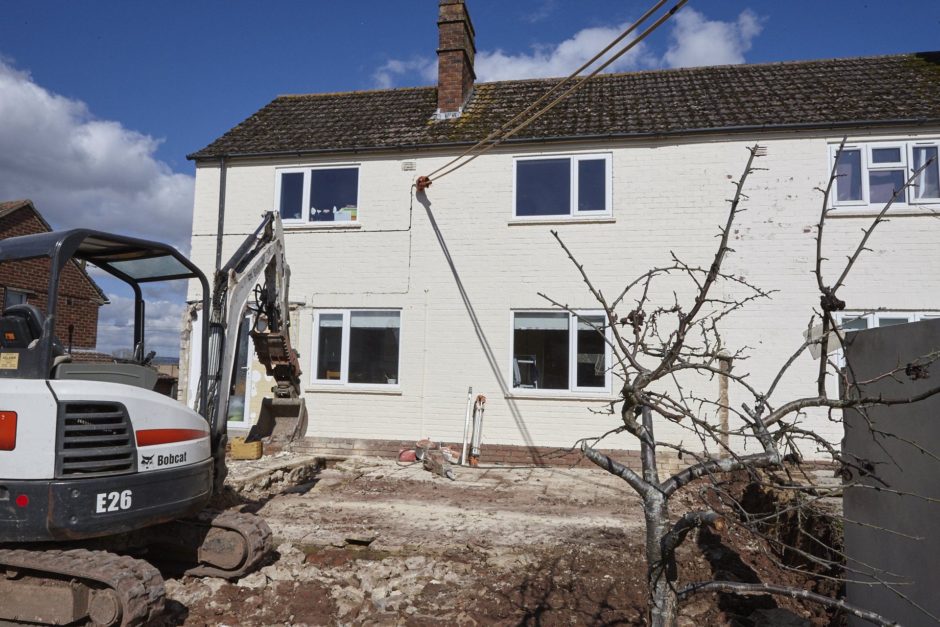 A bobcat excavator is parked in front of a white house