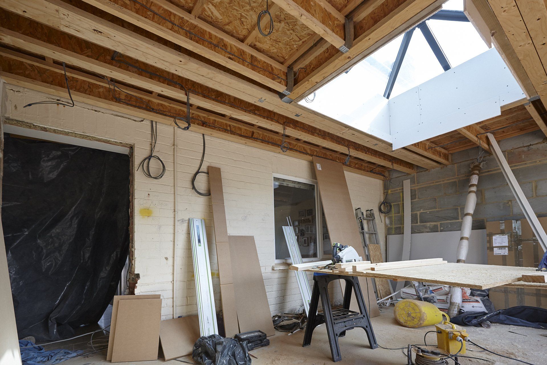 A room under construction with a table and a skylight in the ceiling.