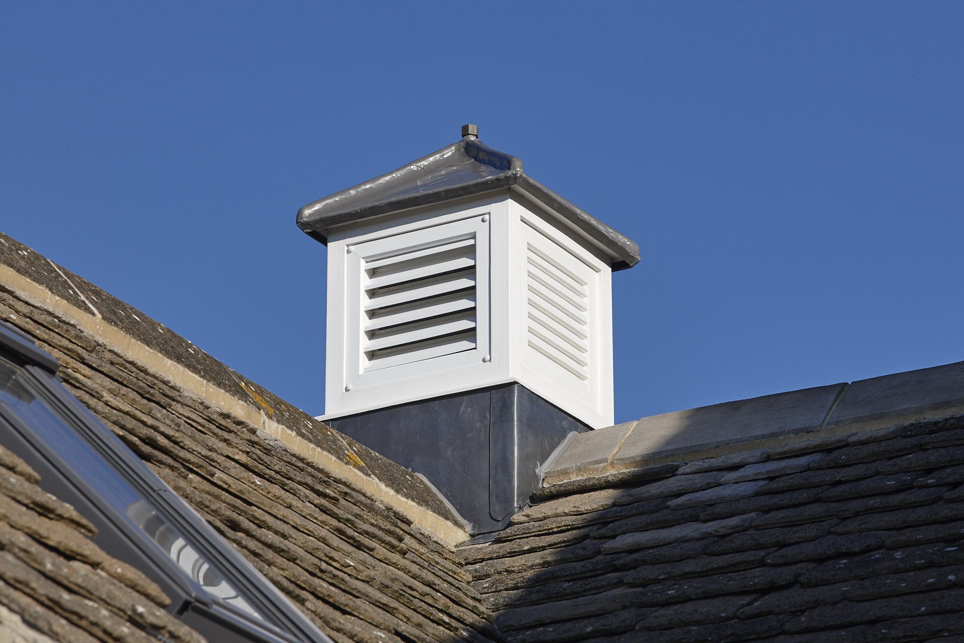A white chimney on top of a roof with a blue sky in the background