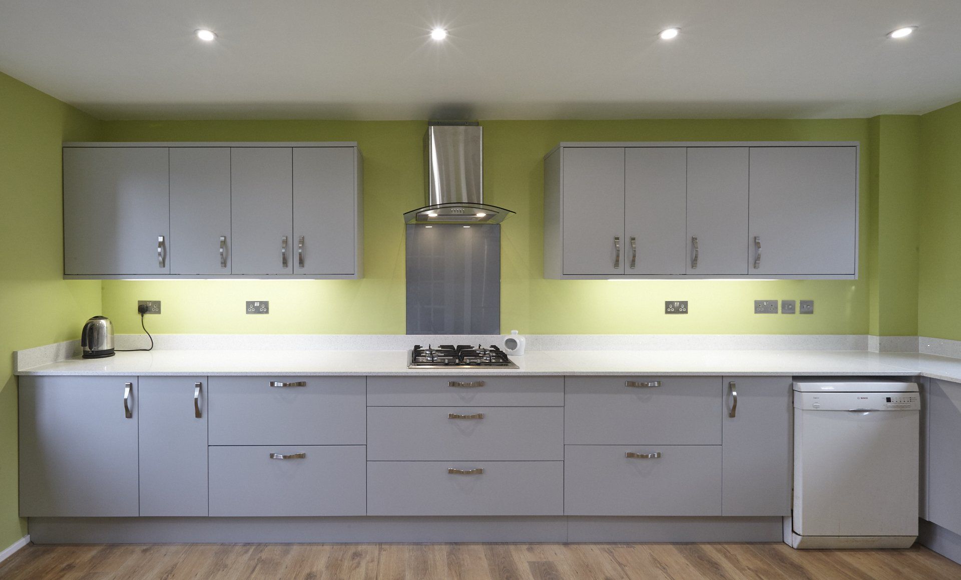 A kitchen with white cabinets and green walls