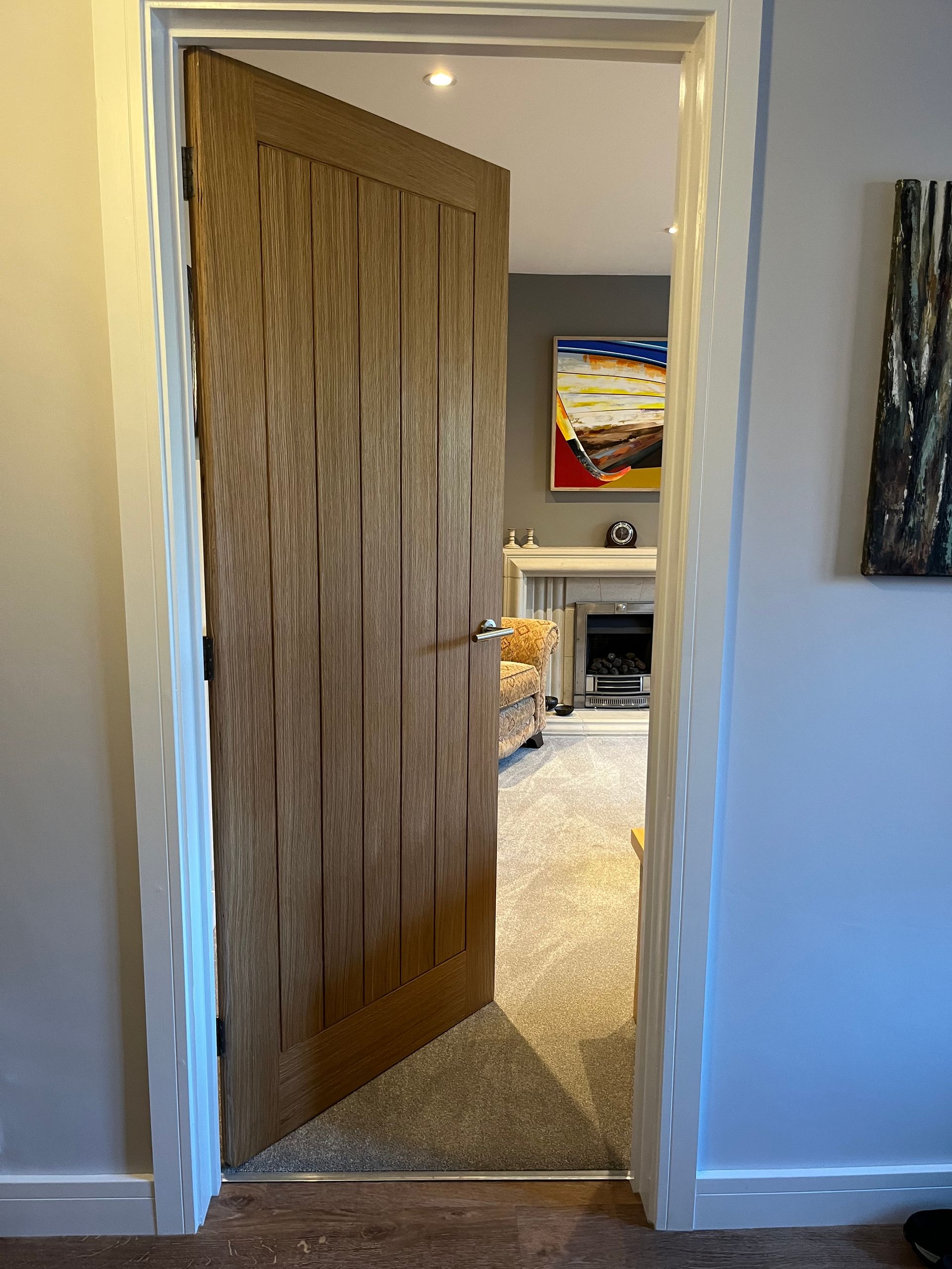A wooden door is open to a living room with a couch and fireplace.