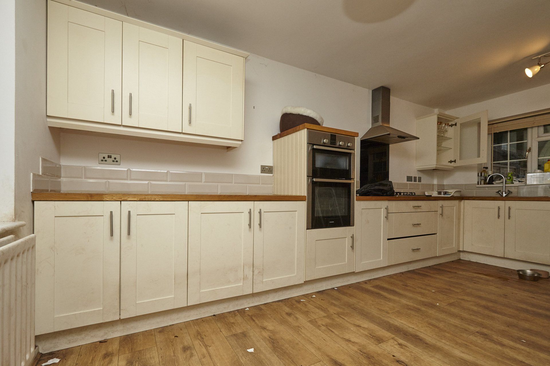 An empty kitchen with white cabinets and wooden floors.