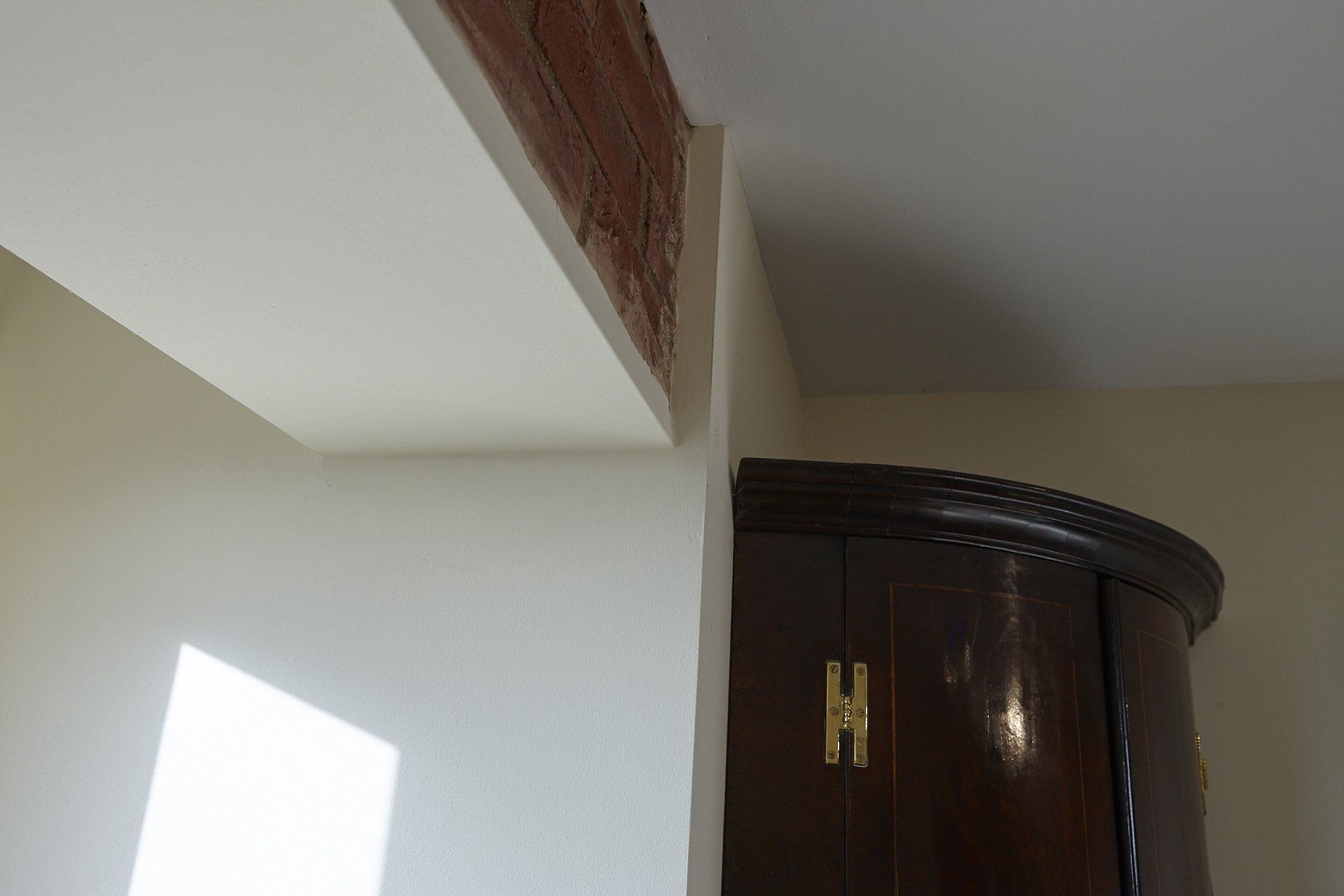 A wooden cabinet is sitting next to a white wall in a room.
