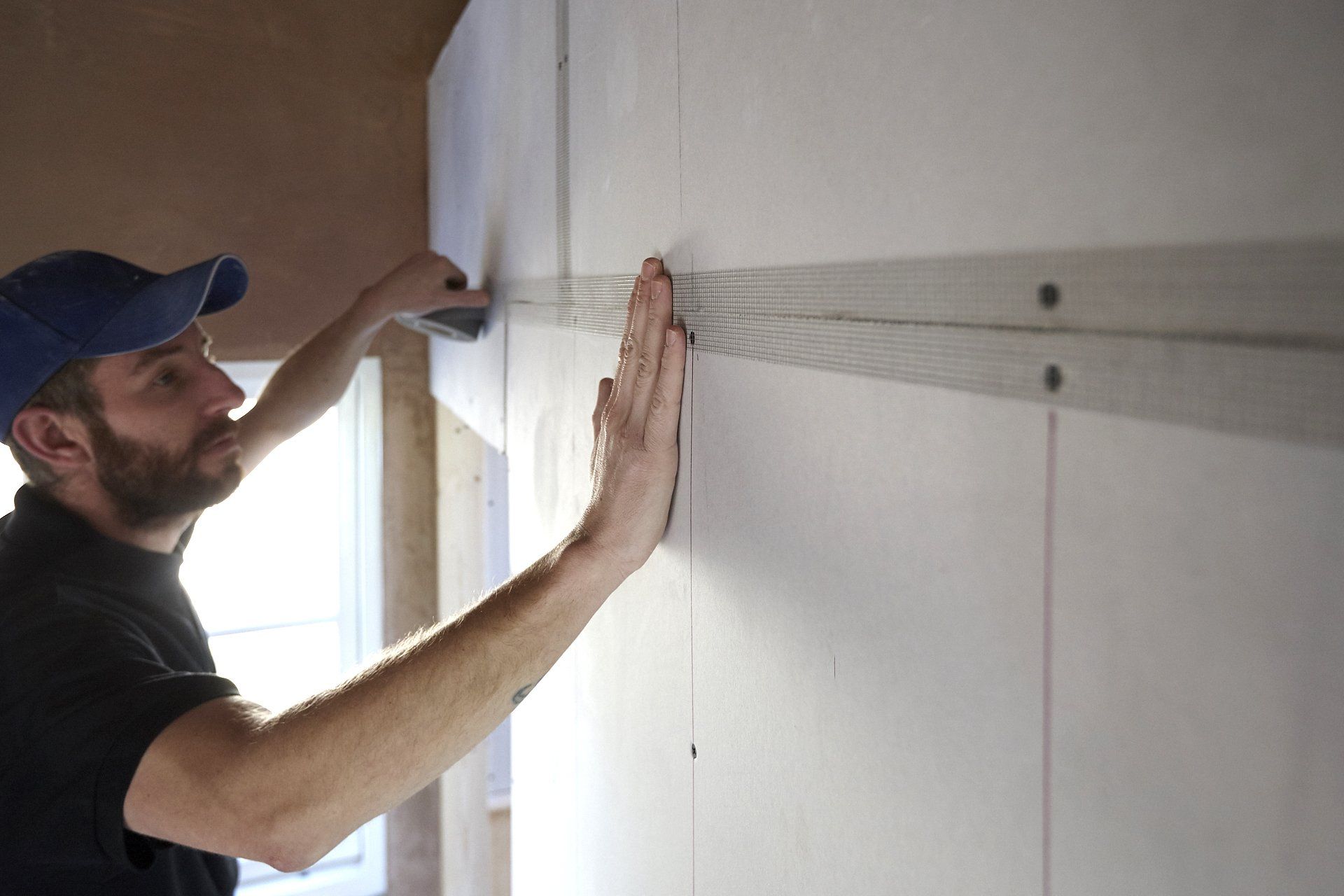 A man is measuring a wall with a tape measure.