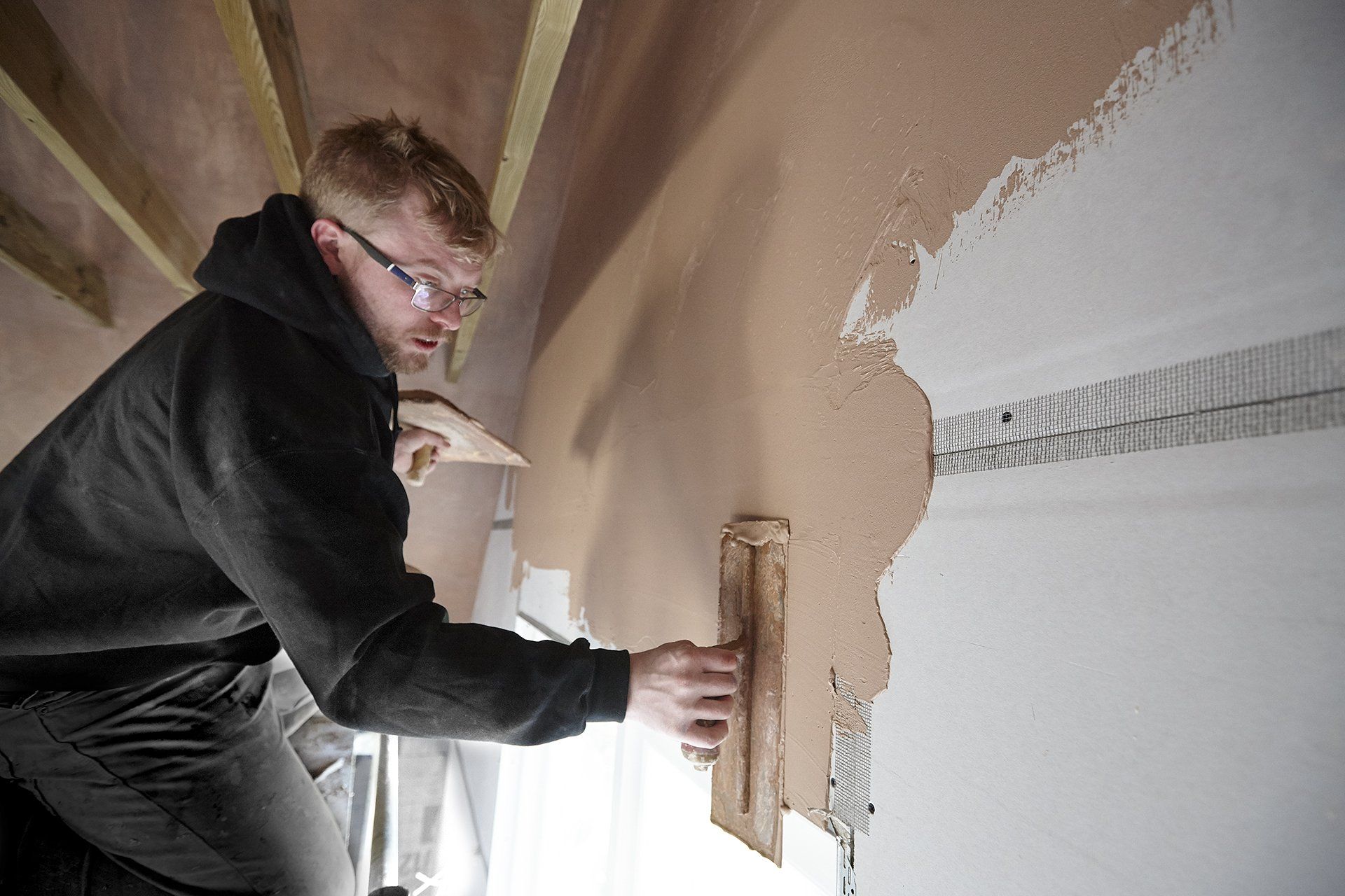 A man is plastering a wall with a trowel.