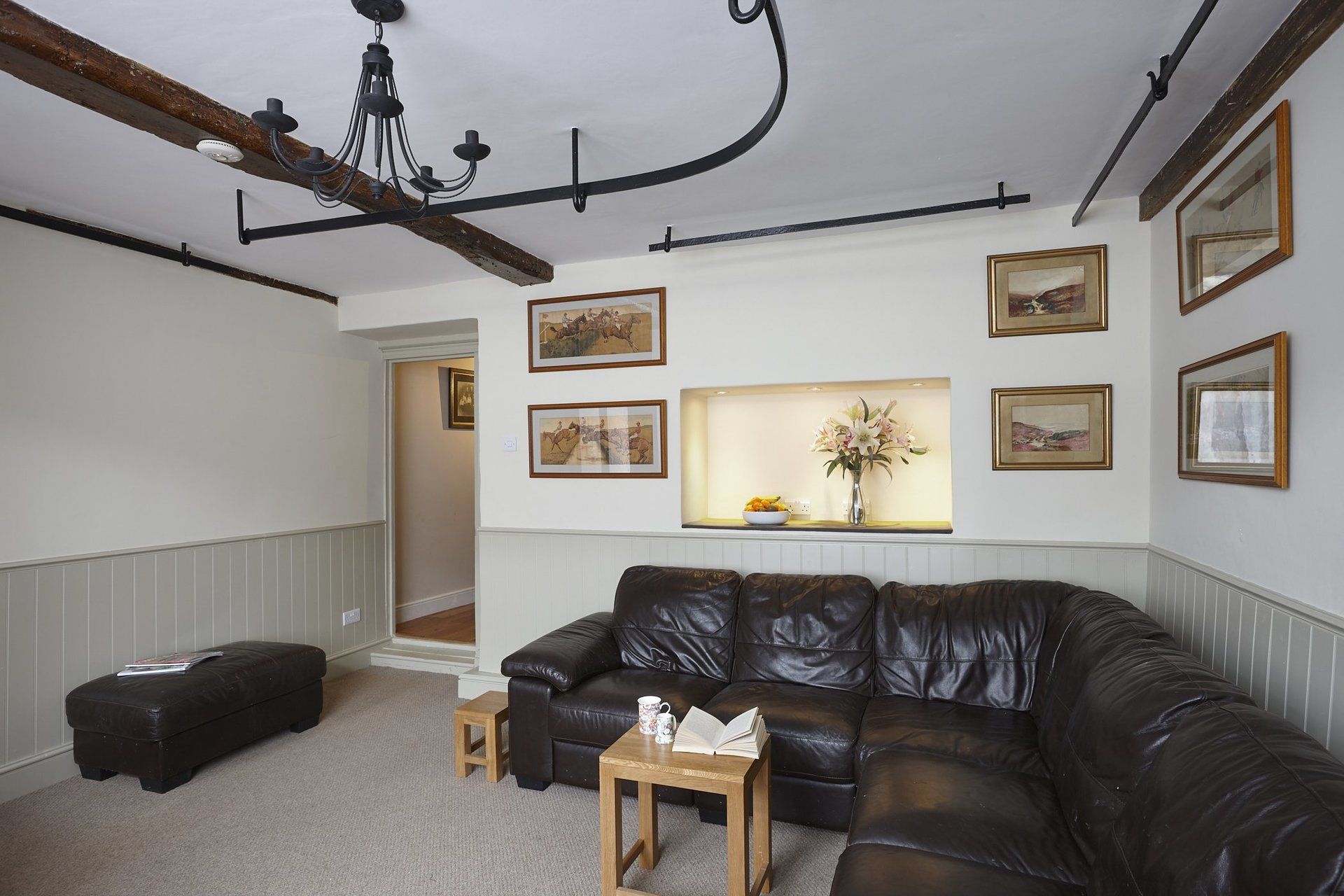 A living room with a brown leather couch and a chandelier