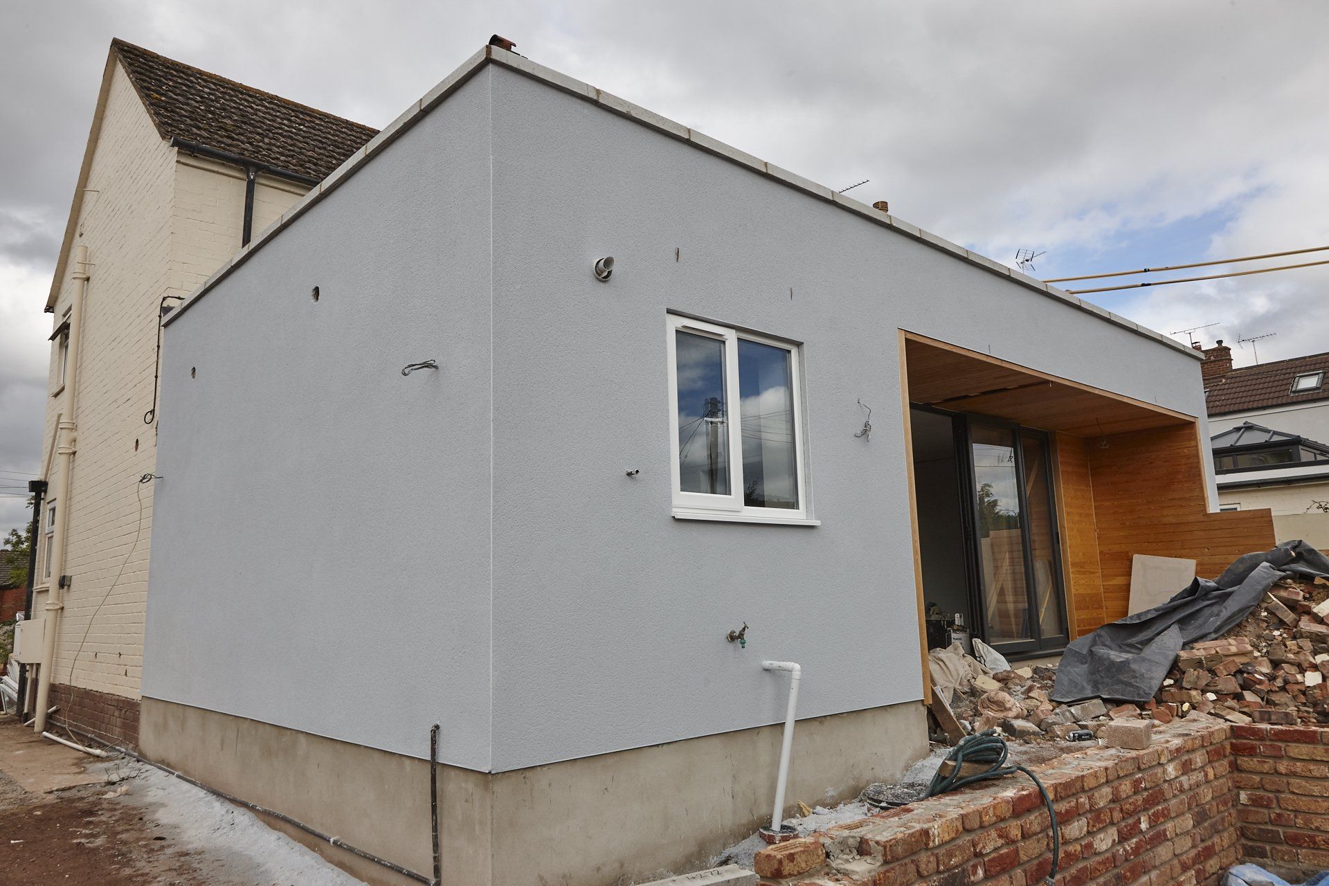 A small white house is being built next to a brick wall.