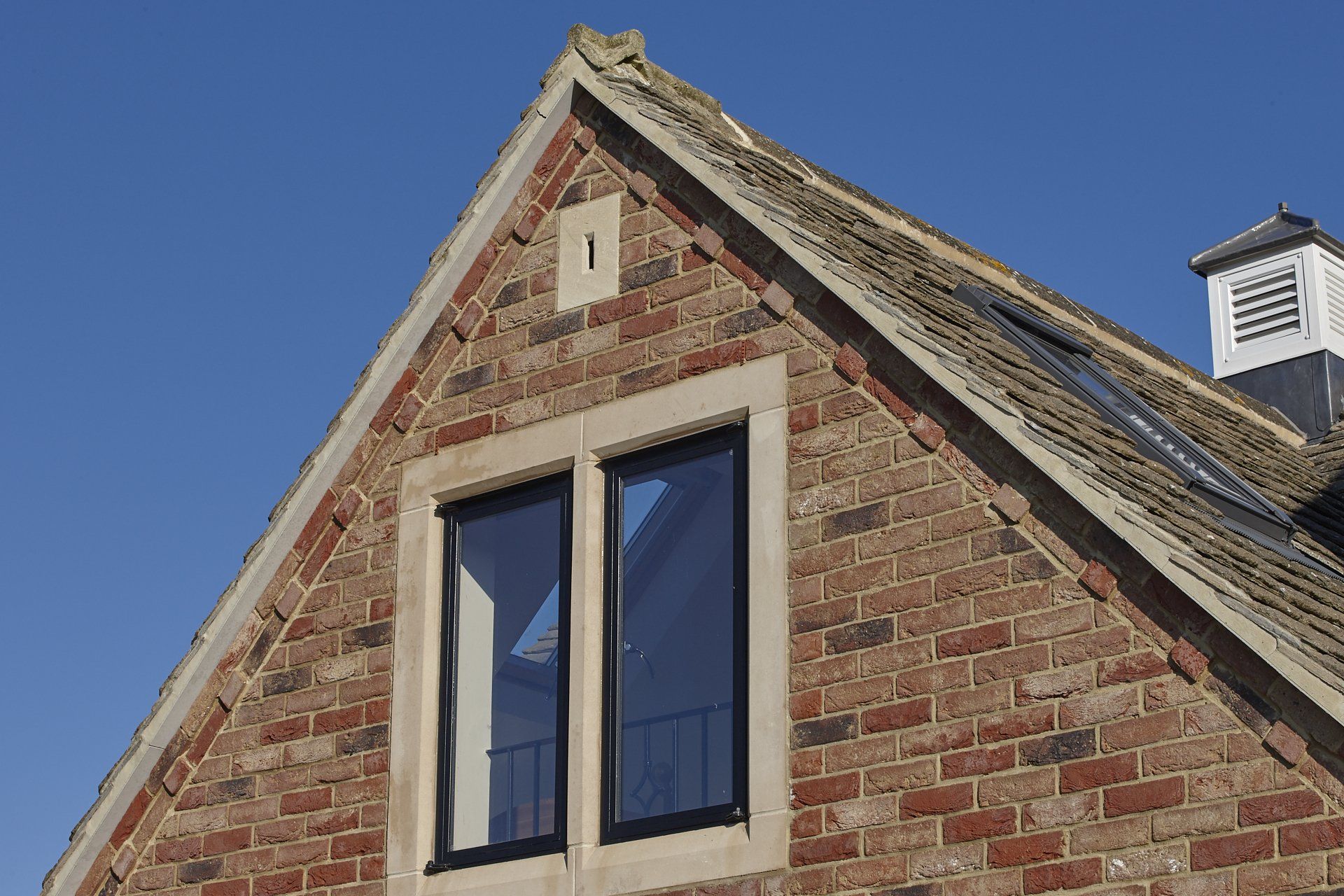 A brick building with two windows and a chimney on top