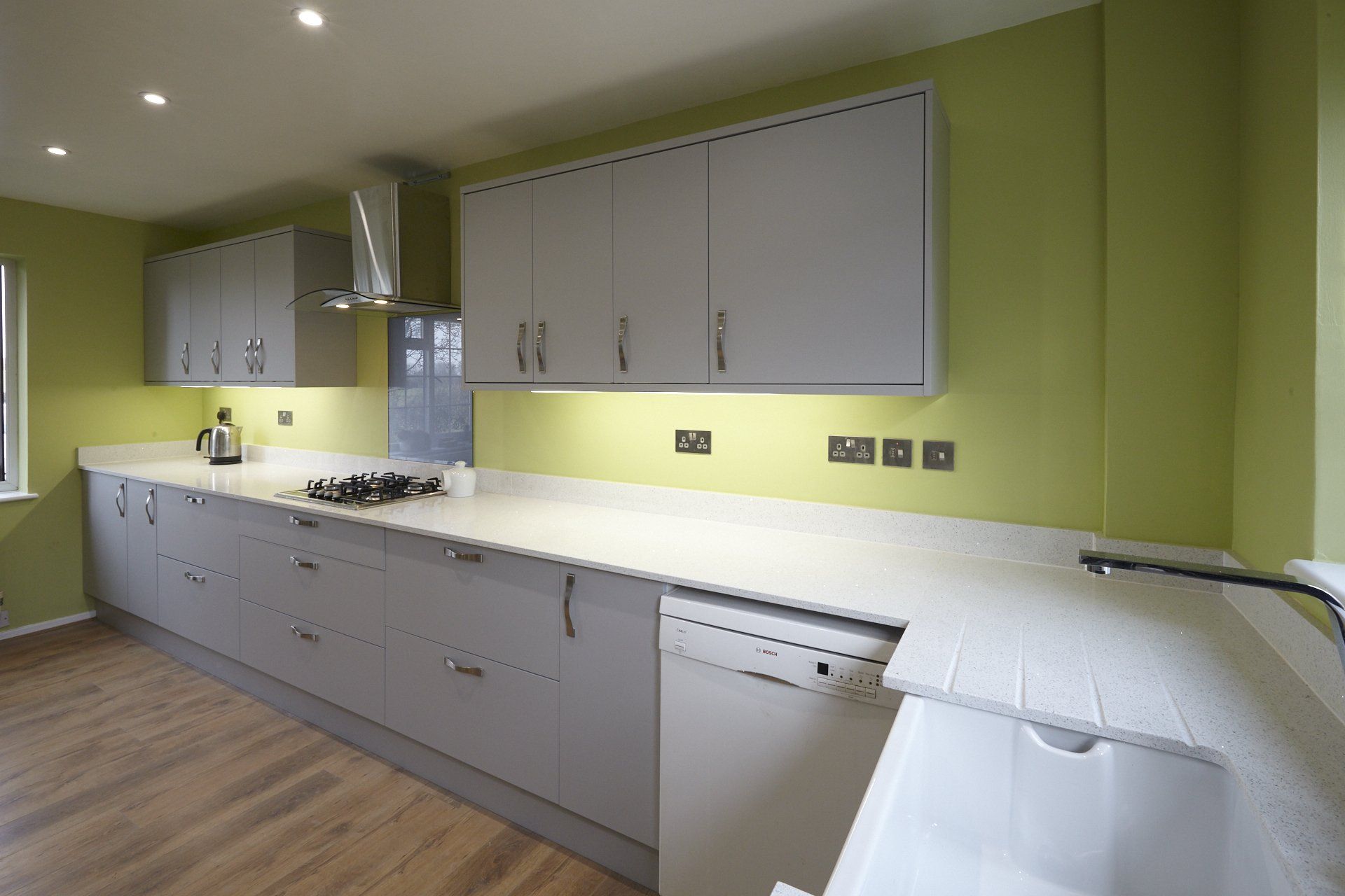 A kitchen with green walls and white cabinets and a sink.
