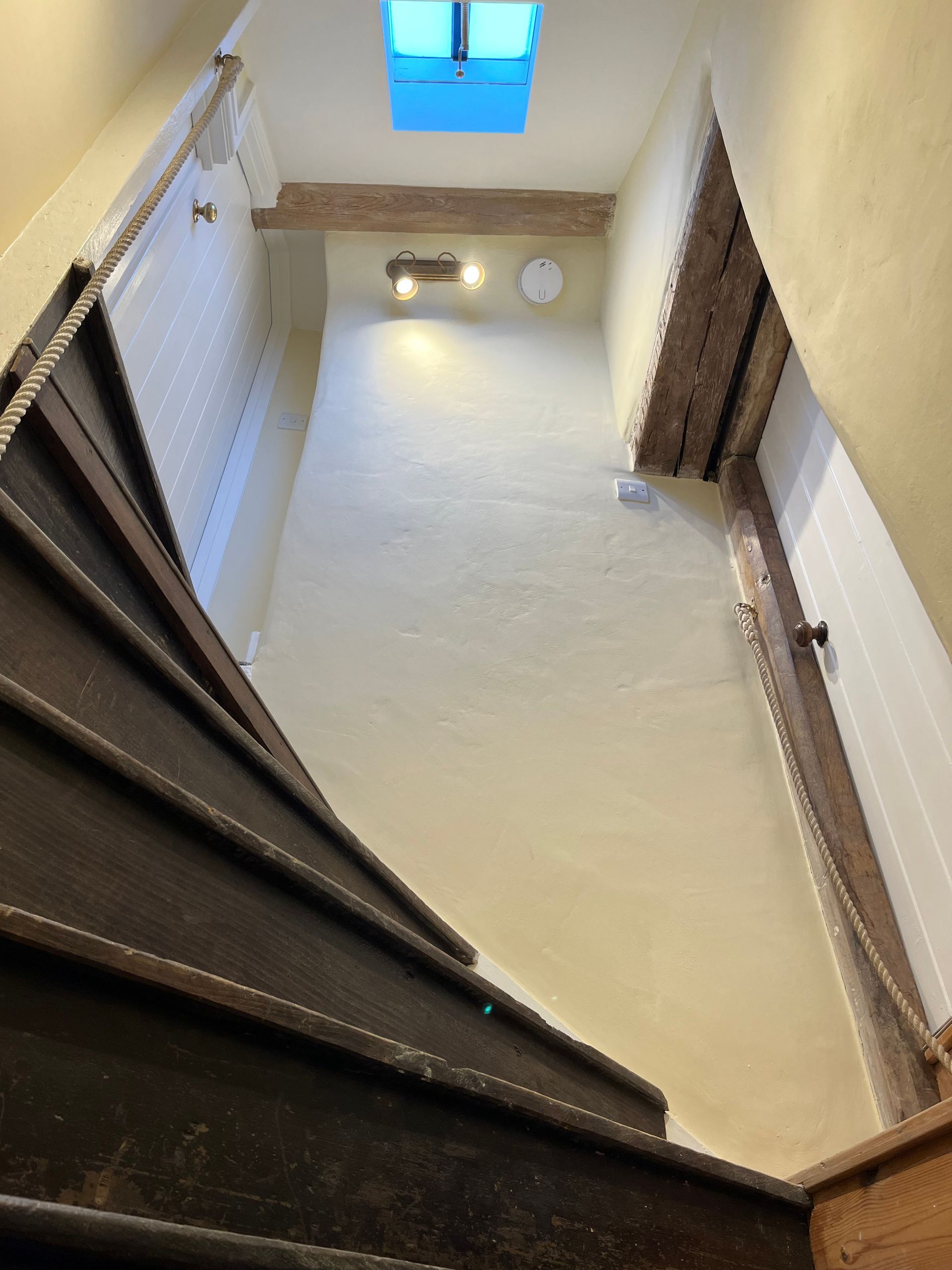 Looking down a staircase with a skylight in the ceiling