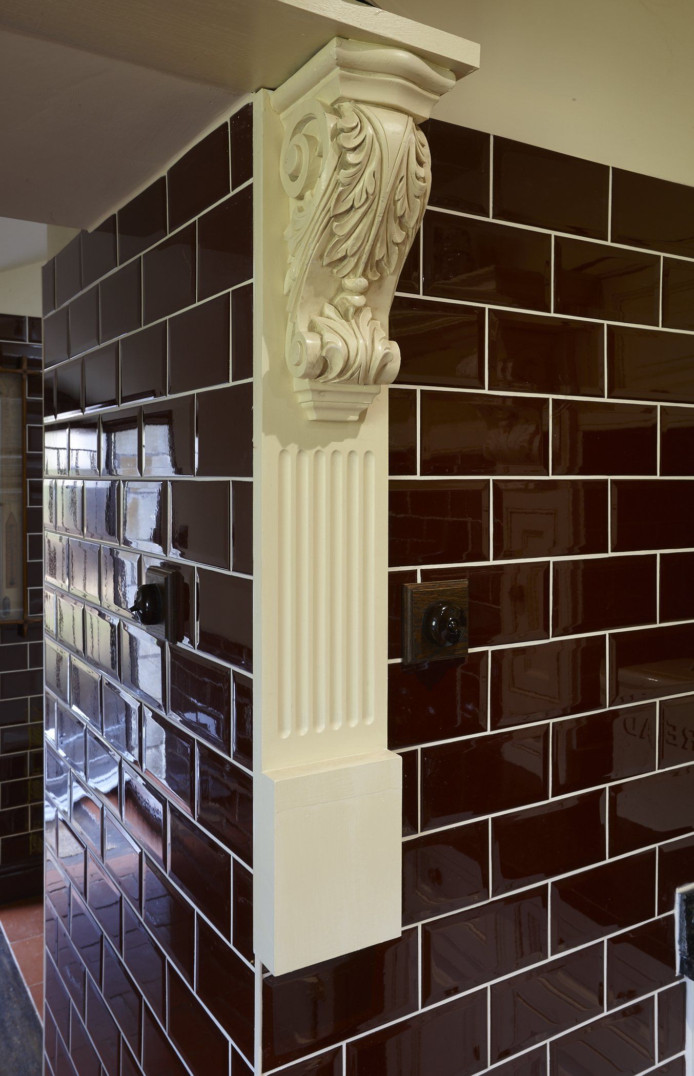 A corner of a room with black tiles and a white pillar