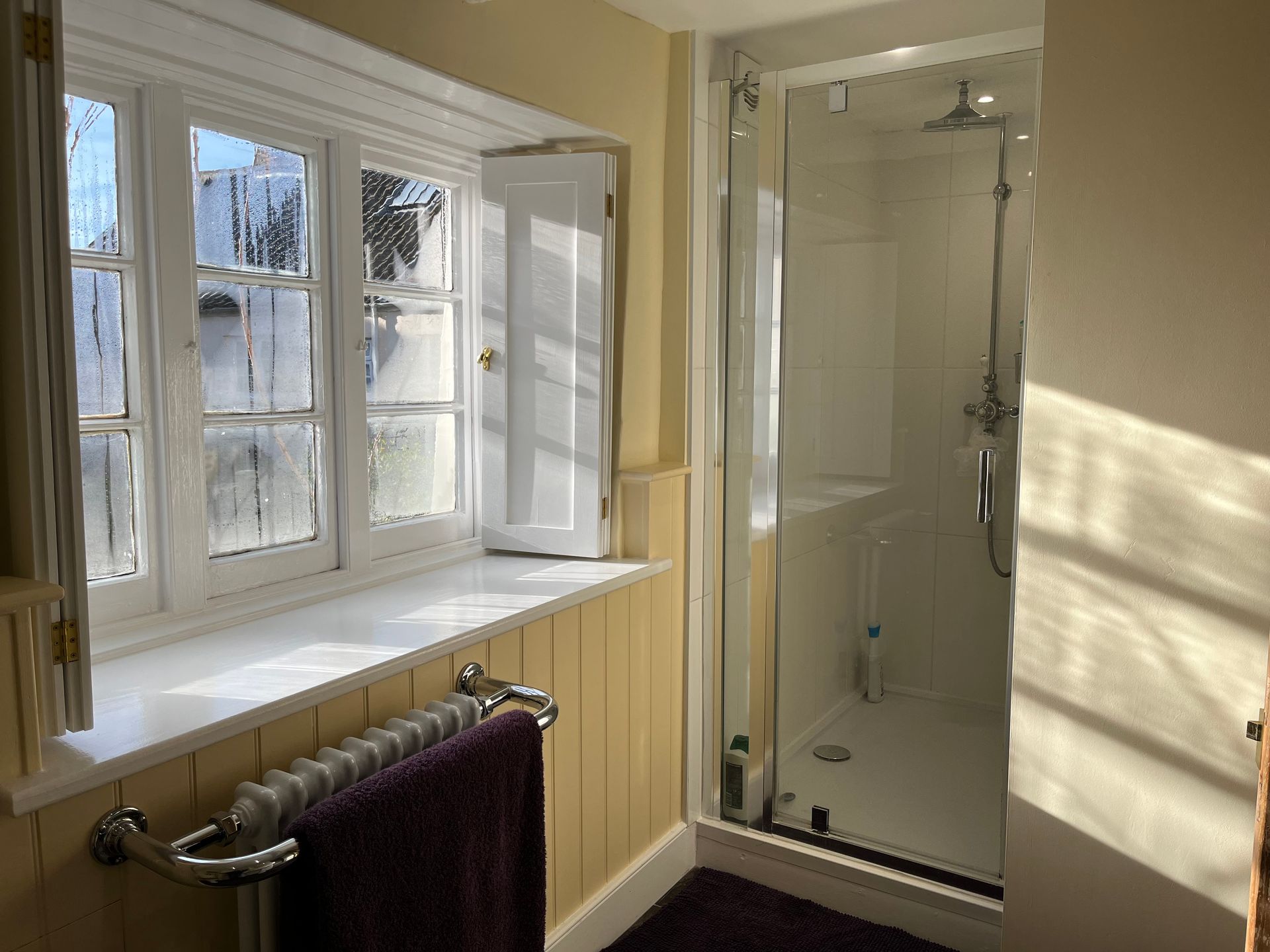A bathroom with a walk in shower and a window.