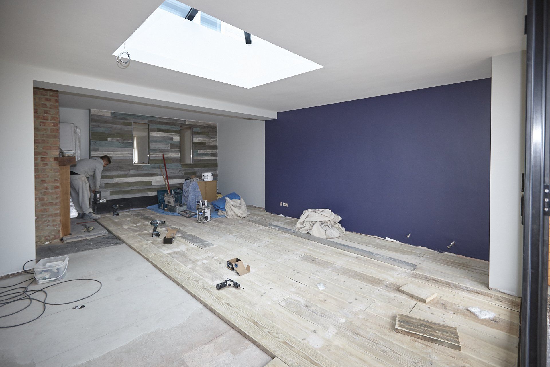 An empty room with a blue wall and a skylight