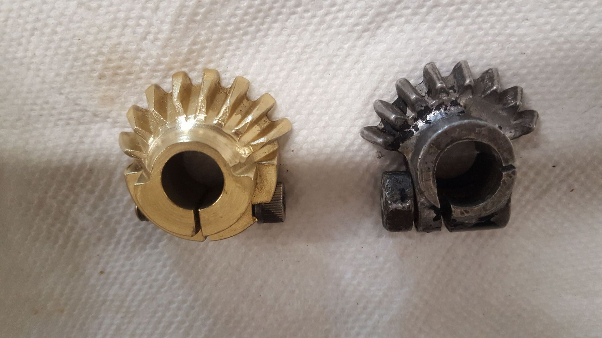 Two metal gears are sitting next to each other on a white cloth.