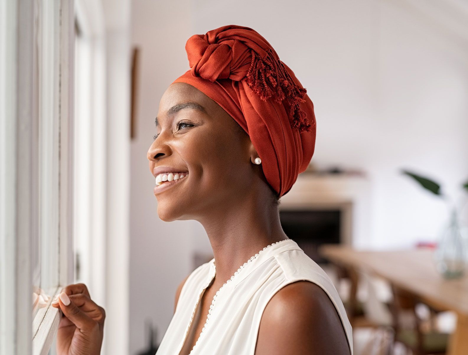 A woman wearing a head scarf is looking out of a window.