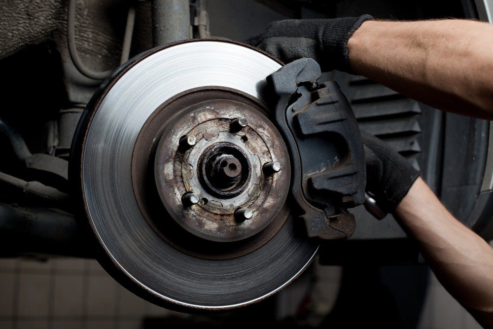 A person is fixing a brake pad on a car.