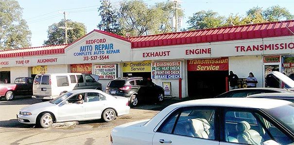 A lot of cars are parked in front of an auto repair shop.