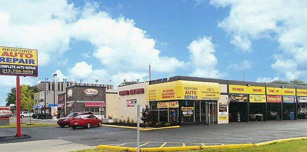 A red car is parked in front of a building that says recycling auto repair