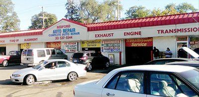 A lot of cars are parked in front of a car repair shop.