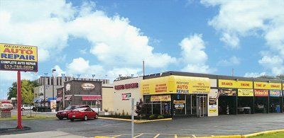 A red car is parked in front of an auto repair shop