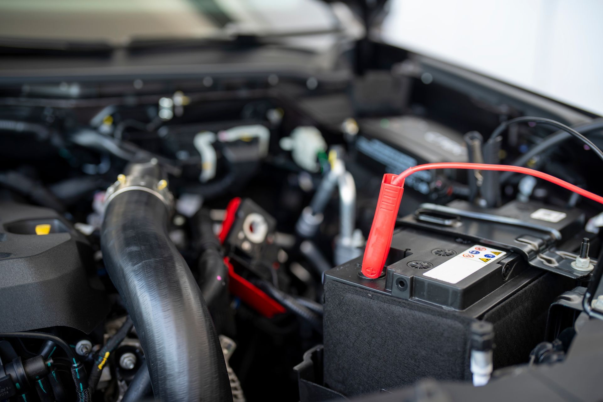 A close up of a car engine with a battery being charged.