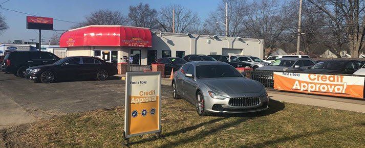 A car dealership with a lot of cars parked in front of it.