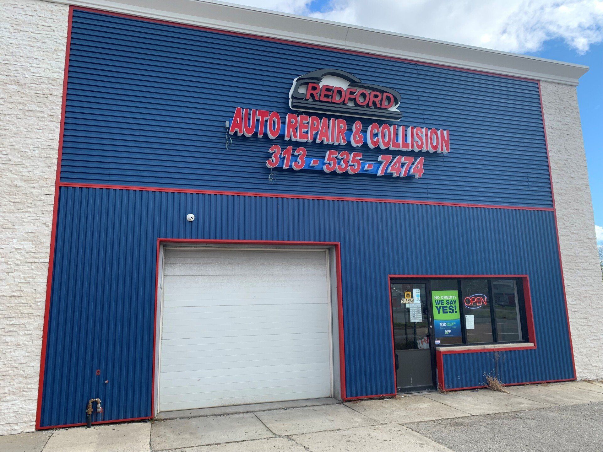 A blue building with red letters that says auto repair and collision