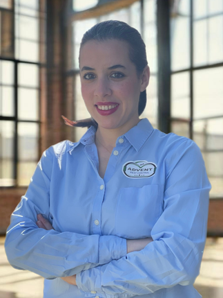 A woman in a blue shirt is posing for a picture with her arms crossed.