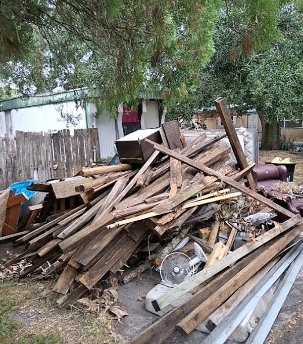 Grapple truck loading mixed junk, wood scraps, and bulky debris during a cleanup in Polk County, Florida.