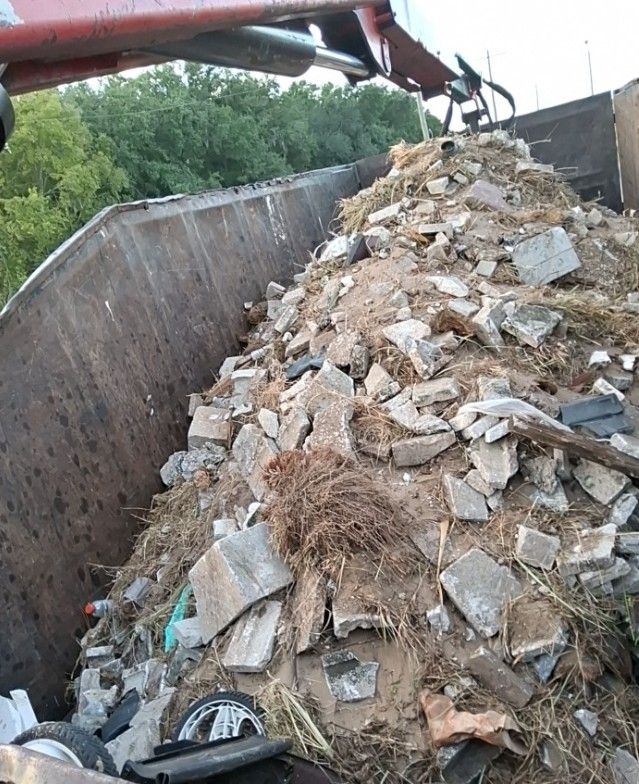 Dirt, rocks, and mixed debris being loaded into a grapple truck during a cleanup project in Poinciana, Florida