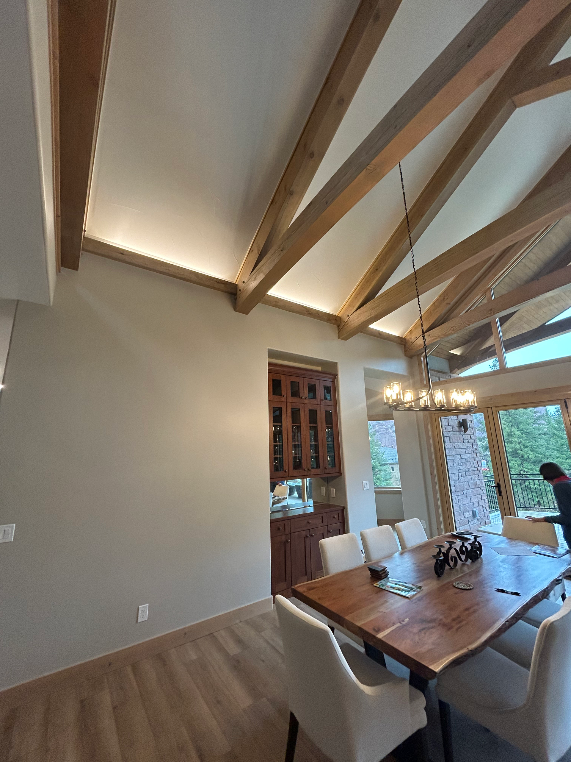 Dining room with wood ceiling beams, a table, chairs, and cabinets.