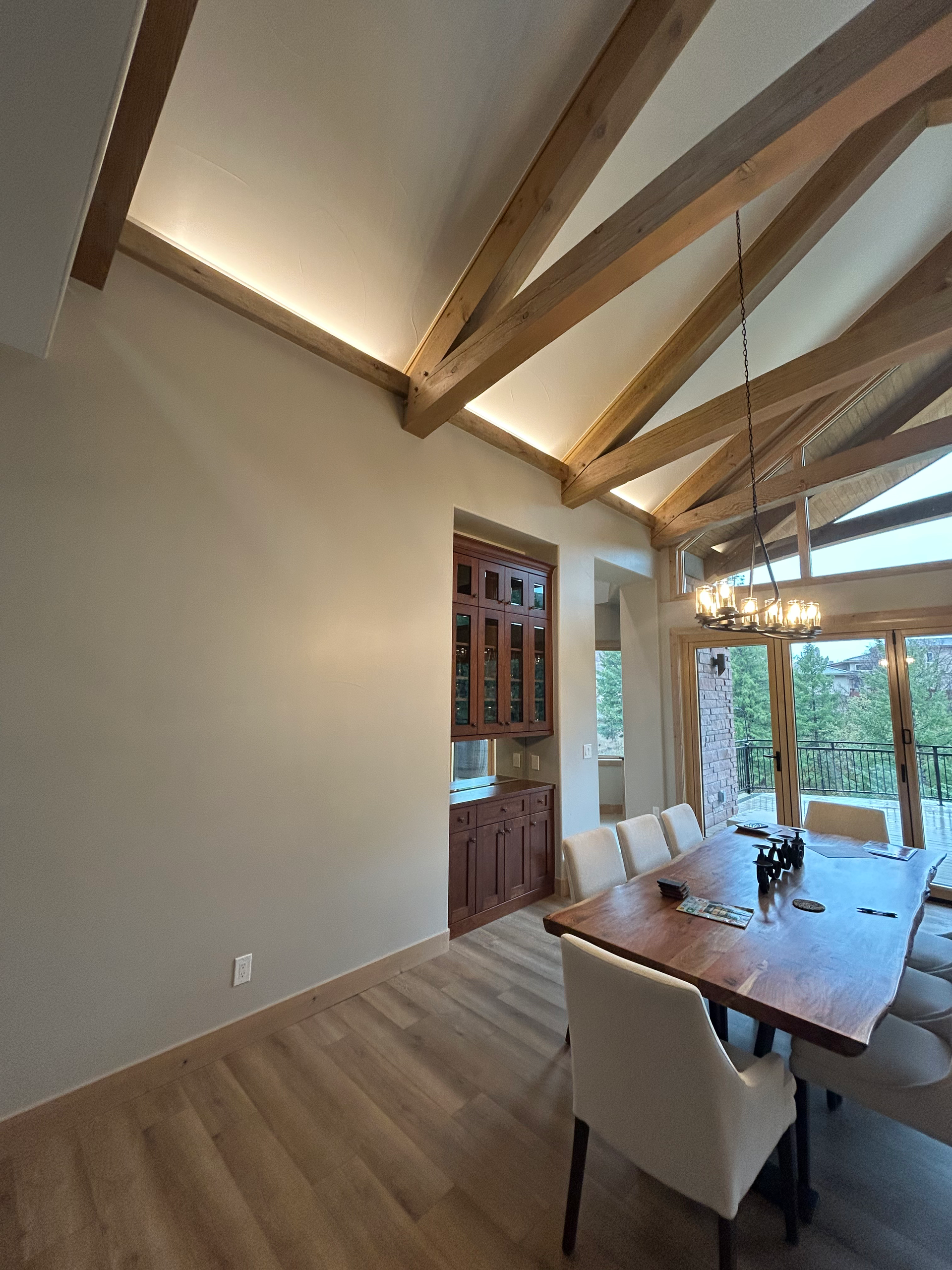 Dining room with wooden beams, a long table, chairs, and a built-in wine cabinet.